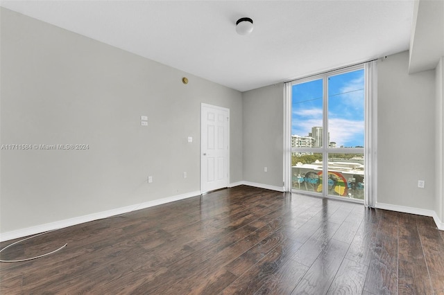 unfurnished room with a wall of windows and dark wood-type flooring