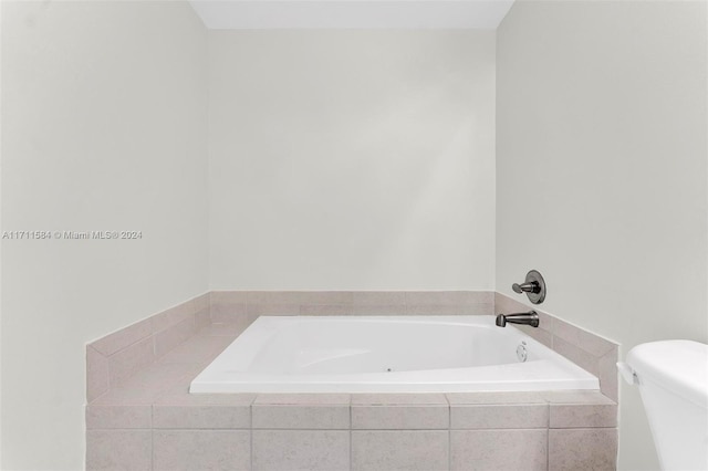 bathroom featuring a relaxing tiled tub and toilet