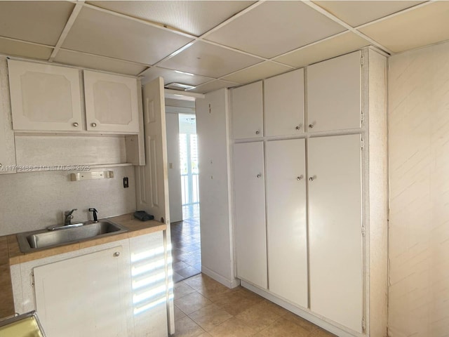 kitchen with a paneled ceiling, sink, and white cabinets