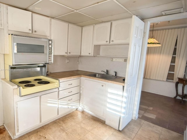 kitchen with a drop ceiling, decorative light fixtures, sink, and white cabinets