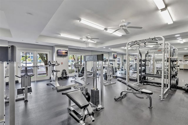 exercise room with french doors, a tray ceiling, and ceiling fan