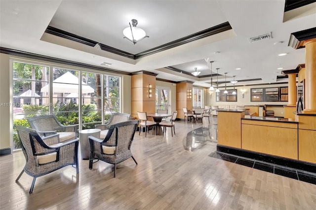 dining room with hardwood / wood-style floors, a raised ceiling, and crown molding