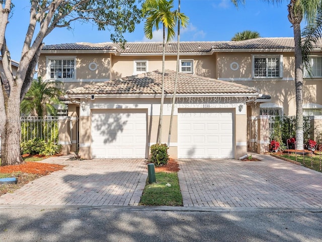 multi unit property with a tiled roof, driveway, stucco siding, and fence