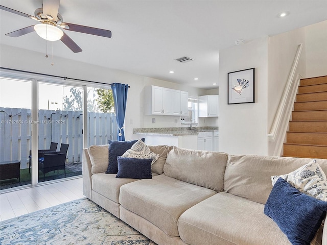living room featuring recessed lighting, light wood-style flooring, stairs, visible vents, and ceiling fan