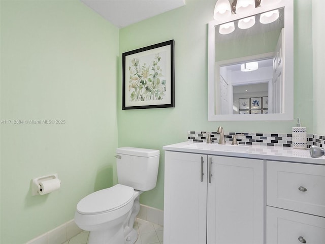 bathroom featuring baseboards, toilet, vanity, backsplash, and tile patterned flooring