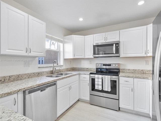 kitchen with light wood-style flooring, white cabinetry, recessed lighting, appliances with stainless steel finishes, and a sink