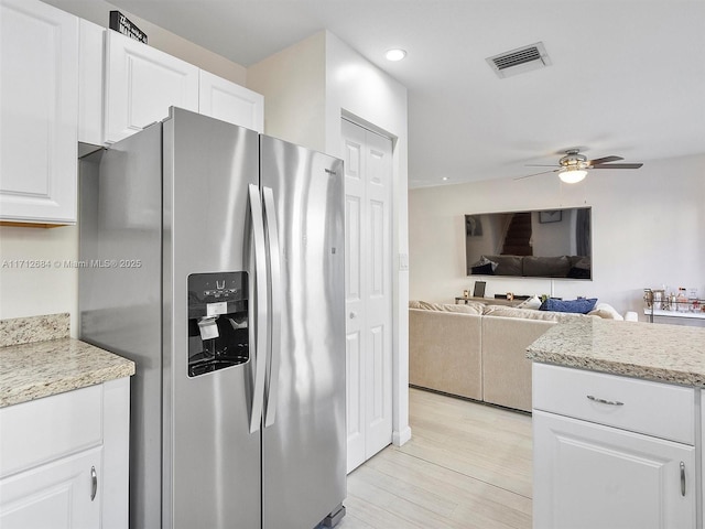 kitchen with stainless steel fridge, white cabinetry, visible vents, ceiling fan, and light wood finished floors