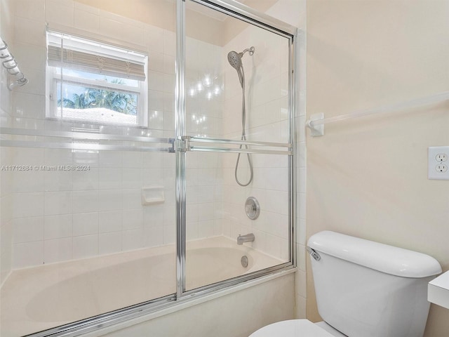 bathroom with toilet and bath / shower combo with glass door