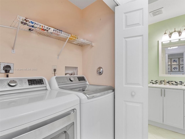 clothes washing area featuring a sink, visible vents, separate washer and dryer, and laundry area