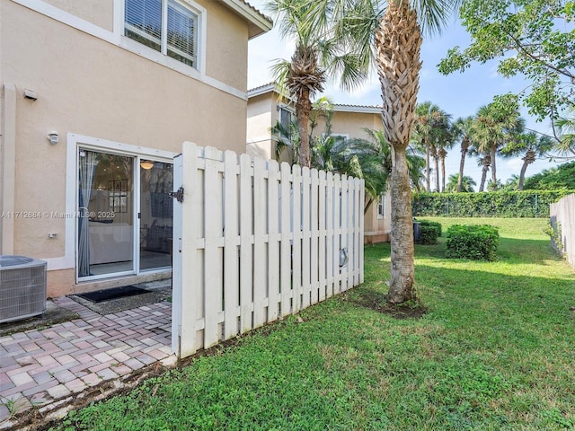 view of gate featuring a yard, cooling unit, and fence