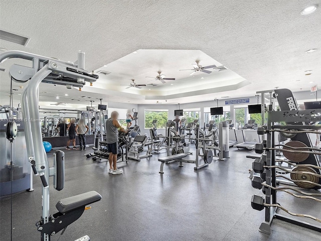 exercise room featuring a raised ceiling and a textured ceiling