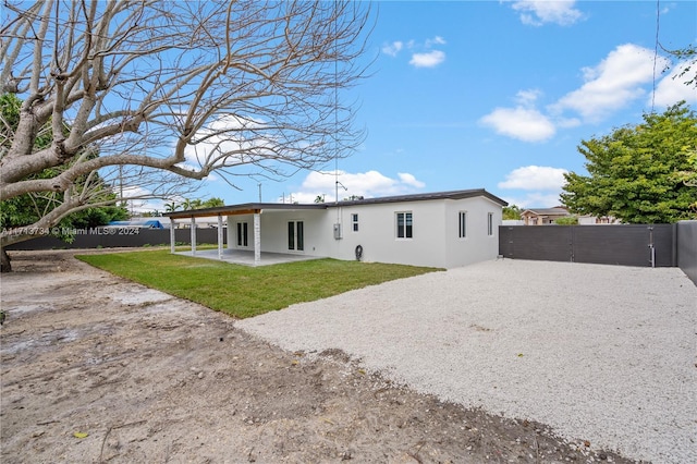 rear view of property featuring a patio and a lawn