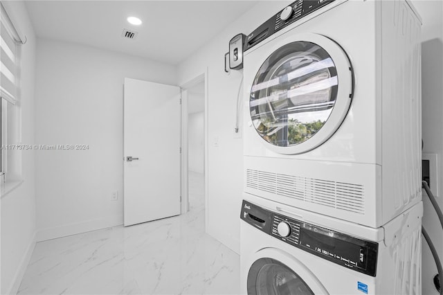 washroom featuring plenty of natural light and stacked washer and clothes dryer