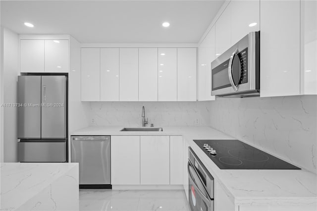 kitchen with sink, white cabinetry, stainless steel appliances, light stone counters, and tasteful backsplash