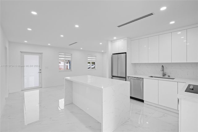 kitchen with appliances with stainless steel finishes, light stone countertops, sink, and white cabinets