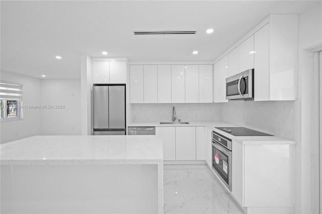 kitchen with white cabinetry, sink, backsplash, and stainless steel appliances