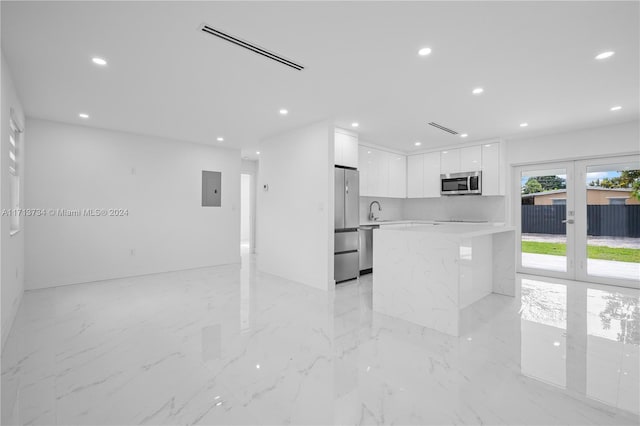 kitchen featuring sink, light stone counters, electric panel, stainless steel appliances, and white cabinets