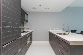 kitchen featuring sink, light tile patterned flooring, and dark brown cabinets