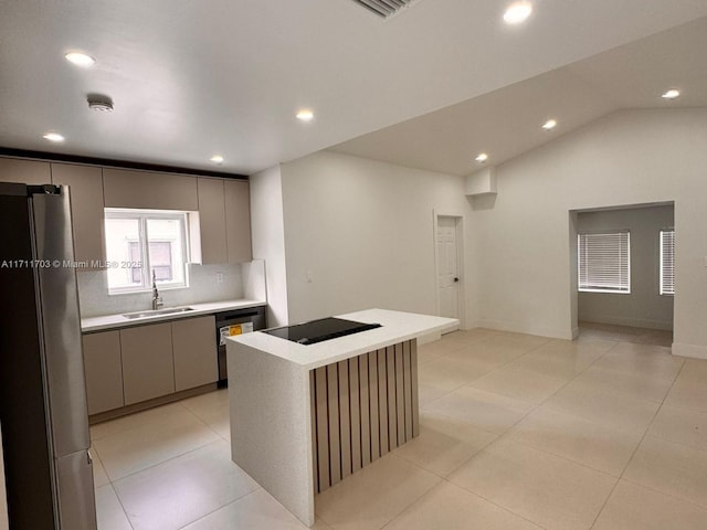 kitchen with light countertops, freestanding refrigerator, a sink, dishwashing machine, and black electric cooktop