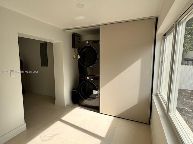 laundry room with stacked washer and dryer, laundry area, electric panel, and tile patterned floors