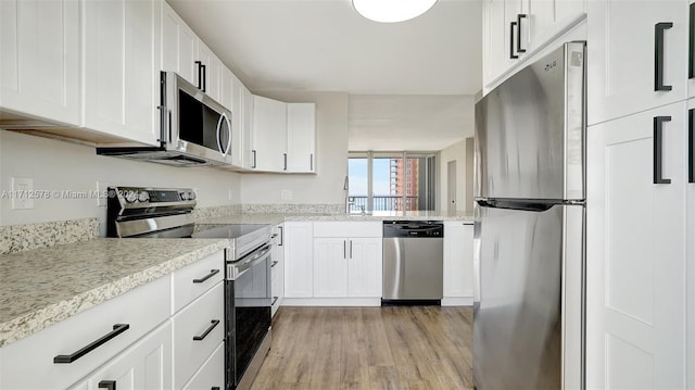 kitchen featuring appliances with stainless steel finishes, light hardwood / wood-style floors, and white cabinetry