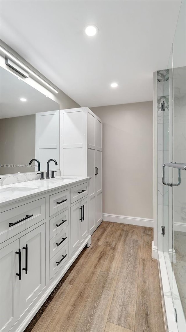 bathroom featuring hardwood / wood-style floors, vanity, and a shower with shower door