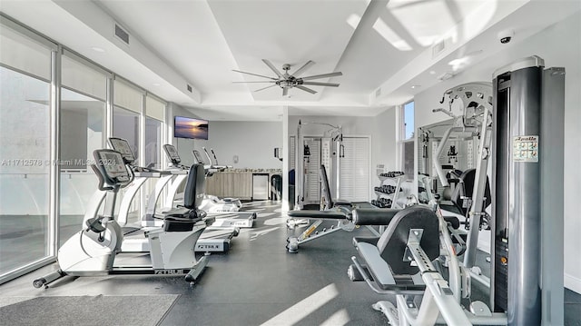 exercise room featuring ceiling fan and a tray ceiling