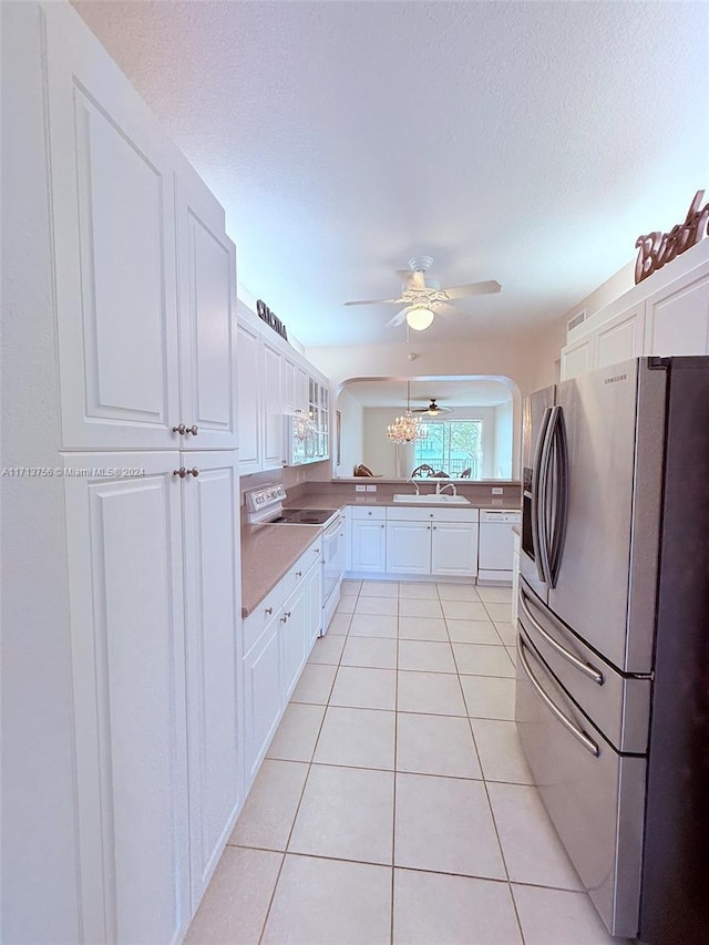 kitchen featuring white appliances, sink, a textured ceiling, light tile patterned flooring, and white cabinetry