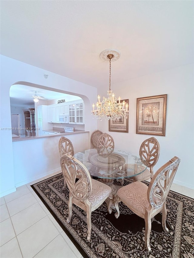 tiled dining space featuring ceiling fan with notable chandelier