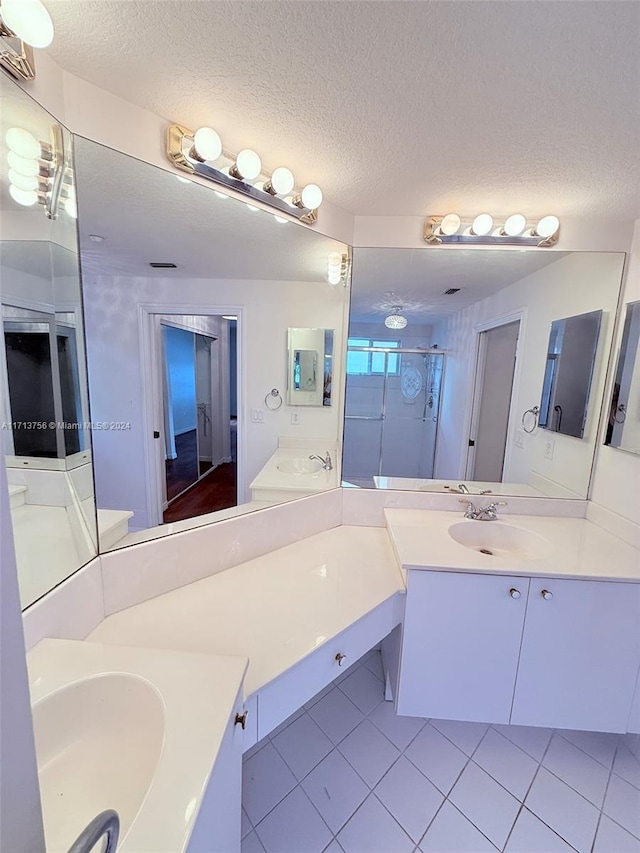 bathroom featuring tile patterned flooring, vanity, an enclosed shower, and a textured ceiling