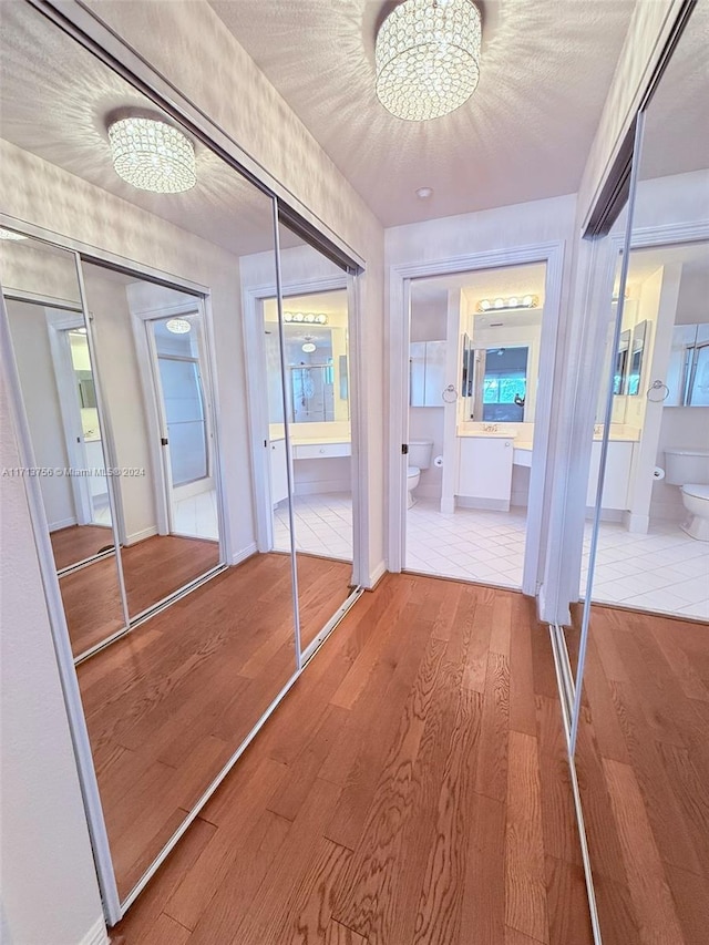 corridor with wood-type flooring, a textured ceiling, and a notable chandelier