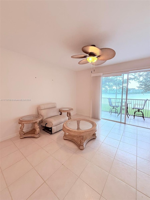 unfurnished room featuring ceiling fan, a water view, and light tile patterned floors