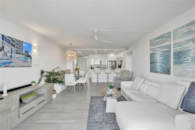 living room featuring light hardwood / wood-style flooring and ceiling fan with notable chandelier