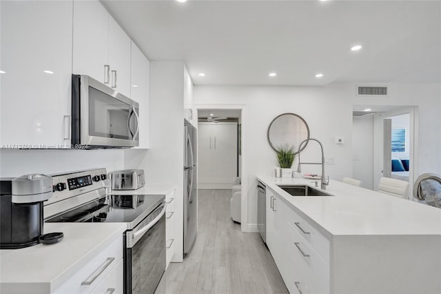 kitchen featuring white cabinets, sink, light hardwood / wood-style flooring, ceiling fan, and stainless steel appliances