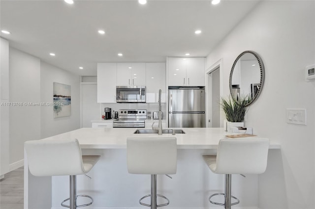 kitchen featuring a breakfast bar, white cabinetry, sink, and appliances with stainless steel finishes