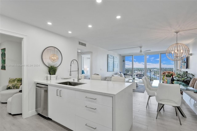 kitchen featuring pendant lighting, floor to ceiling windows, white cabinets, sink, and stainless steel dishwasher