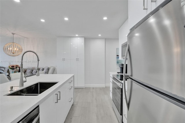 kitchen with white cabinets, stainless steel fridge, sink, and pendant lighting