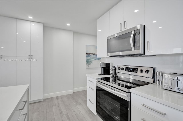 kitchen with white cabinets, stainless steel appliances, and light wood-type flooring