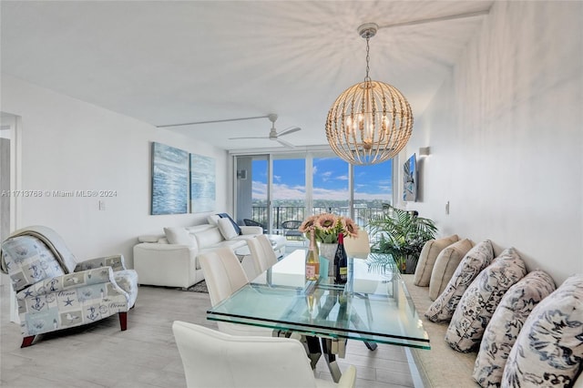 dining area with ceiling fan with notable chandelier, expansive windows, and light hardwood / wood-style floors