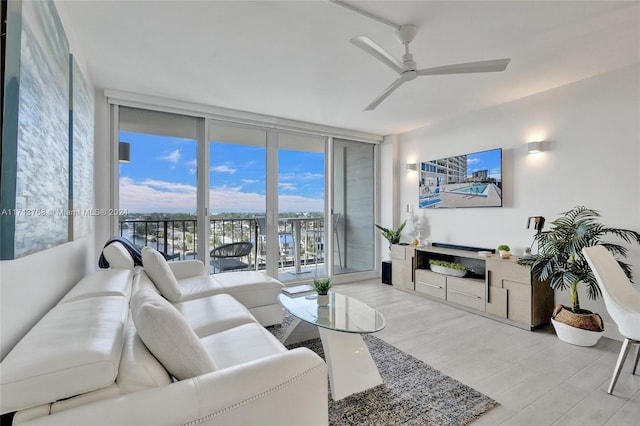 living room with ceiling fan, floor to ceiling windows, and light hardwood / wood-style flooring