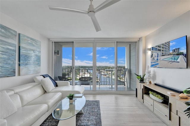 living room featuring ceiling fan, floor to ceiling windows, and light hardwood / wood-style flooring