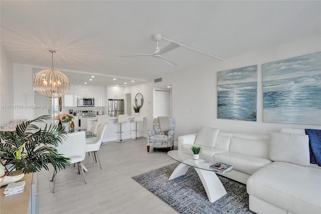 living room featuring ceiling fan with notable chandelier