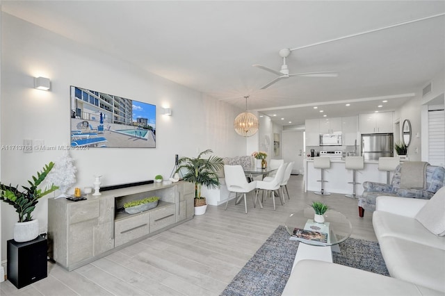 living room featuring light hardwood / wood-style floors and ceiling fan with notable chandelier