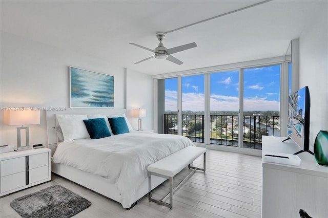 bedroom with access to outside, ceiling fan, light hardwood / wood-style flooring, and a wall of windows