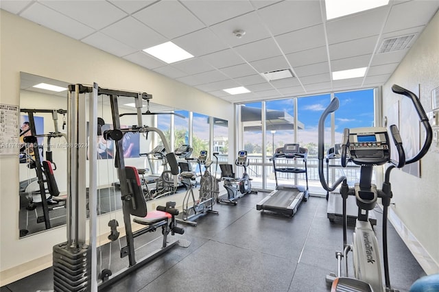 workout area with a drop ceiling, expansive windows, and a wealth of natural light