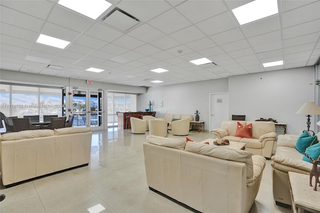 living room with french doors, a paneled ceiling, and light tile patterned flooring