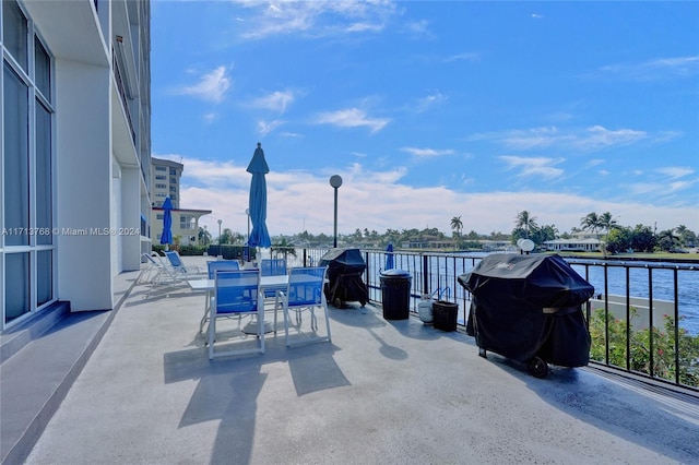 view of patio with a water view, a balcony, and grilling area