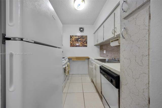 kitchen featuring white appliances, white cabinets, sink, light tile patterned floors, and tasteful backsplash