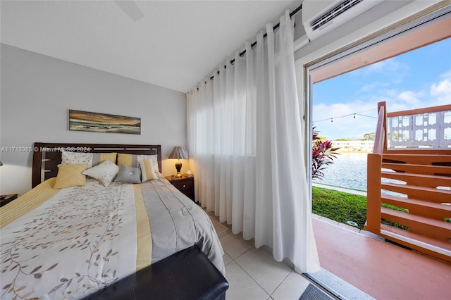 bedroom with light tile patterned floors, a water view, an AC wall unit, and lofted ceiling