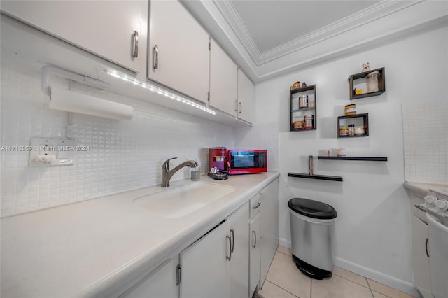 kitchen featuring sink, decorative backsplash, light tile patterned floors, ornamental molding, and white cabinetry